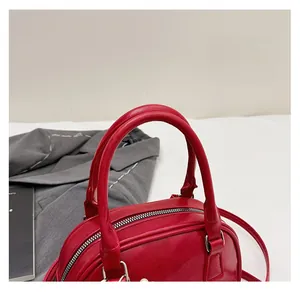 Detail of red bowling bag handle and zipper closure with detachable shoulder strap