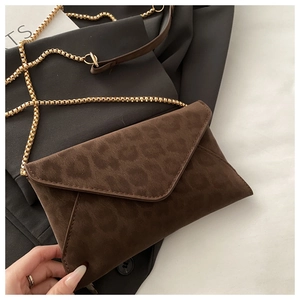 Détail de la pochette léopard avec une chaîne à billes dorée et une texture suédée mate