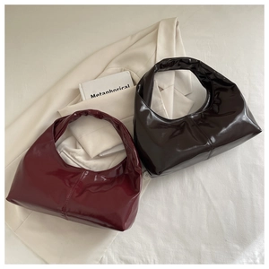 Detail of glossy patent leather hobo bags in wine red and chocolate brown colors