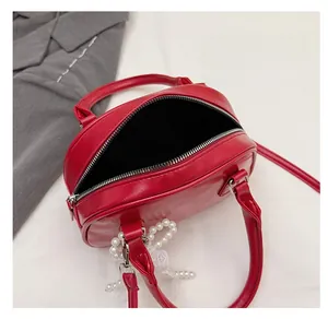 Detail view of the red PU leather handbag interior with zipper and pearl lace charm