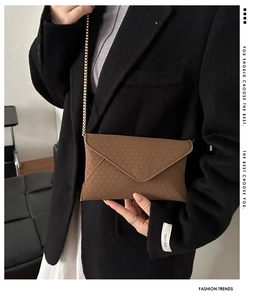 Detailed close-up of brown envelope bag with V-shaped woven texture and gold chain strap