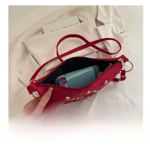 Détail du sac à main en daim rouge avec rivets dorés montrant la capacité intérieure