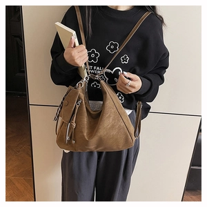 Detail of dark brown vintage frosted leather bag with metal zippers and dual strap design