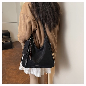 Detail of black Hobo shoulder bag with detachable mini pouch and fringe tassel accessory