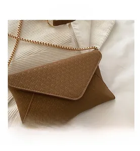 Detail shot of brown envelope crossbody bag with gold chain and textured faux leather