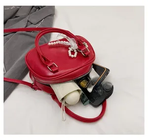 Red mini crossbody bag showing internal capacity for phone, folding umbrella and makeup
