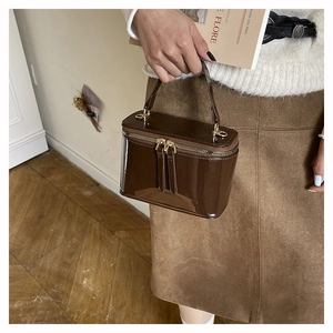 Dettaglio di borsa in vernice marrone cioccolato lucido con cerniere in metallo dorato