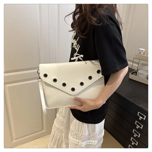 Detail view of a white envelope clutch bag with metal eyelets and a vintage rivet design