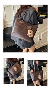 Detail of vintage brown leather tote bag featuring a plush bear charm and striped ribbon