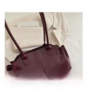 Macro view of burgundy glossy leather shoulder bag with vertical stitching and dual straps