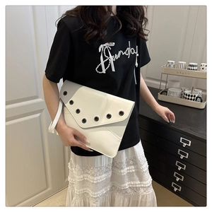 Detail showing white envelope clutch bag with black metal grommets and carrying strap