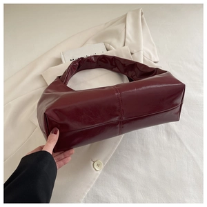 Detail view of burgundy glossy patent leather tote with vertical stitch and smooth texture