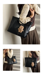 Detail view of black glossy faux leather tote bag with cute brown plush bear charm