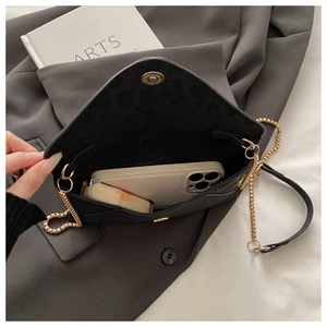 Vue intérieure du sac enveloppe noir montrant sa capacité pour téléphone et maquillage