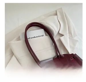 Detail shot of the dark red underarm bag with smooth oil wax texture and soft handle