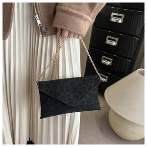 Détail d'une pochette léopard grise avec chaîne dorée portée par un mannequin chic
