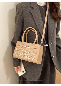Detail of minimalist beige embroidered handbag with silver clasp on grey blazer outfit