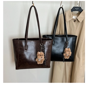 Detail of minimalist tote bags with soft grain texture and plush bear charm accents