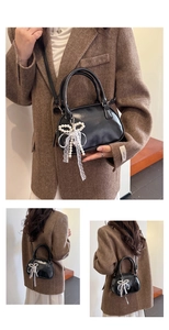 Détail d'un sac à main noir semi-circulaire avec nœud perlé et ruban de dentelle