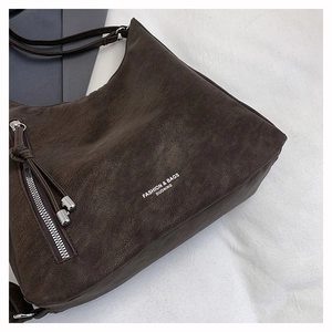 Close-up of dark brown pebbled leather texture with silver zipper and tassel detail