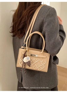 Détail du sac à main beige brodé avec fermoir argenté et pendentif de mode décoratif