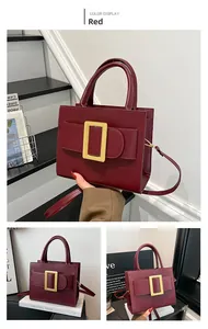 Close-up of structured wine red handbag featuring a large matte gold square metal buckle