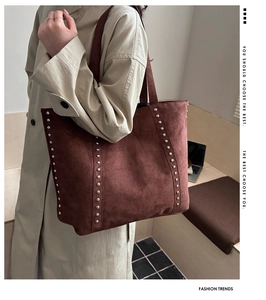 Detail view of large dark brown suede tote bag featuring vertical silver stud accents