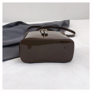 Detailed bottom view of dark brown patent leather crossbody bag with precision stitching