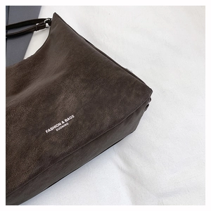 Detail of dark brown leather tote showing pebble texture and white fashion logo print