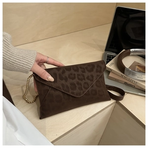 Détail d'une pochette léopard marron foncé avec une élégante chaîne à perles dorées