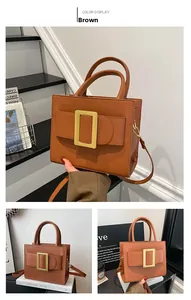 Detail view of structured brown handbag featuring a large golden square buckle decoration