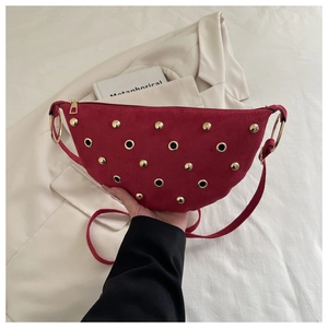 Détail du sac demi-lune en daim rouge avec rivets dorés et anneau métallique