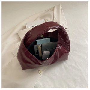 Detail view of burgundy patent leather hobo bag showing spacious interior with personal items