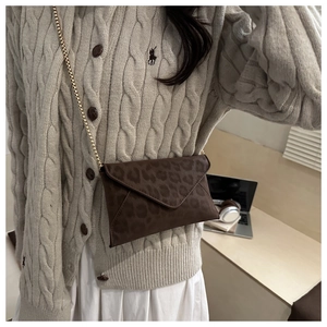 Détail du petit sac bandoulière enveloppe avec imprimé léopard marron et chaîne dorée