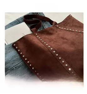 Detailed view of dark brown suede tote bag featuring retro metal rivet accents and texture