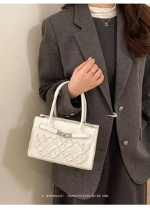 Détail d'un sac blanc rétro avec motifs floraux gaufrés et fermoir métallique