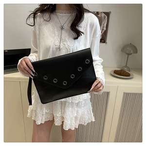 Detail of black vintage rivet clutch bag with V-shaped metal eyelets and side strap