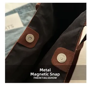 Close-up of magnetic silver buckle and brown suede texture on a tote bag interior