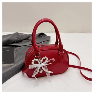 Détail du sac Boston rouge avec breloque en perles et dentelle et anses rondes