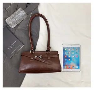 Close-up of vintage brown faux leather shoulder bag with silver buckle on white fabric