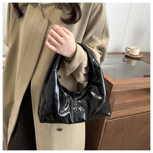 Close-up of black patent leather tote bag with pleated design and minimalist city style