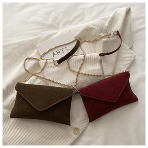 Detail view of woven texture envelope crossbody bags in brown and wine red with gold chains