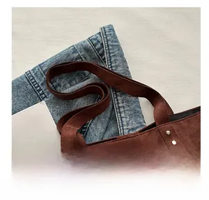Detail view of dark brown suede tote bag featuring silver studs and a comfortable handle