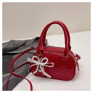 Détail du sac Boston rouge foncé avec bordure en dentelle et pendentif nœud perlé