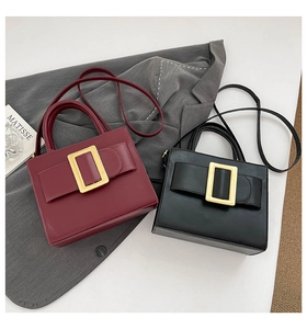 Close-up of the vintage square buckle and leather strap detail on a burgundy handbag