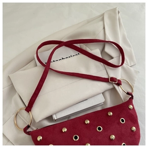 Détail du sac à bandoulière bordeaux en daim avec rivets dorés et anneau en métal
