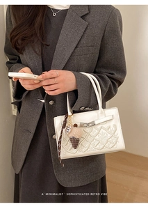 Détail du sac à main en cuir blanc avec broderie florale 3D et fermoir rotatif argenté