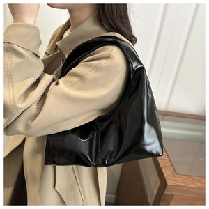 Detail of high-gloss black patent leather shoulder bag with a natural wrinkled texture