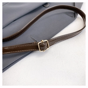 Close-up of brown patent leather shoulder strap with a polished gold adjustable metal buckle