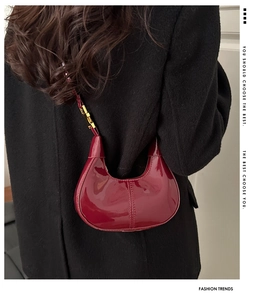 Detailed view of the glossy burgundy leather hobo bag with a gold buckle and crescent shape